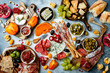 © sveta_zarzamora - Appetizers table with antipasti snacks. Authentic traditional spanish tapas set, cheese and meat platter over grey concrete background. Top view