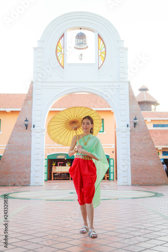 Fotografie, Obraz Young Beautiful Thai Asian woman in vintage Traditional Thai costume with umbrella in wait to welcome guest