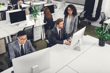 Wall Mural - high angle view of multiracial business people using desktop computers in office