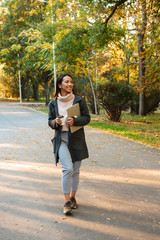 Sticker - Smiling young asian woman wearing coat walking