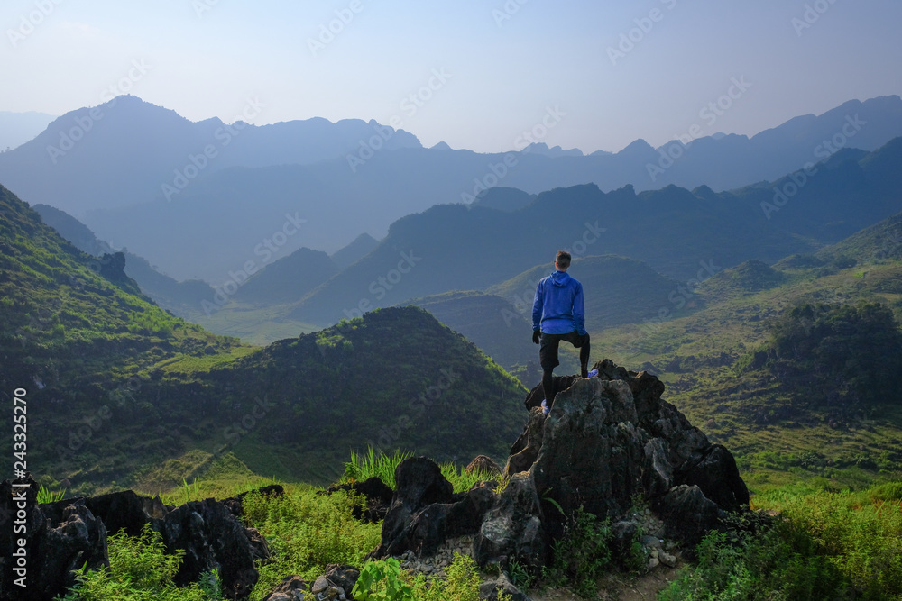 Backpacker standing on outcrop overlooking karst mountain scenery in the North Vietnamese region of Ha Giang / Dong Van - obrazy, fototapety, plakaty 