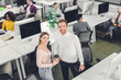 © LIGHTFIELD STUDIOS - high angle view of cheerful young business people smiling at camera while standing in open space office
