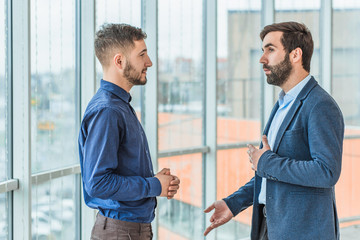 Two businessmen talk about a successful deal. Dressed in business clothes.