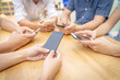 © somchaikhun - group of young man or friends playing online application game in modern touch screen mobile on wood table.