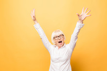 I'm Winner! Portrait Of A Cheerful Senior Woman Gesturing Victory Isolated Over Yellow Background.