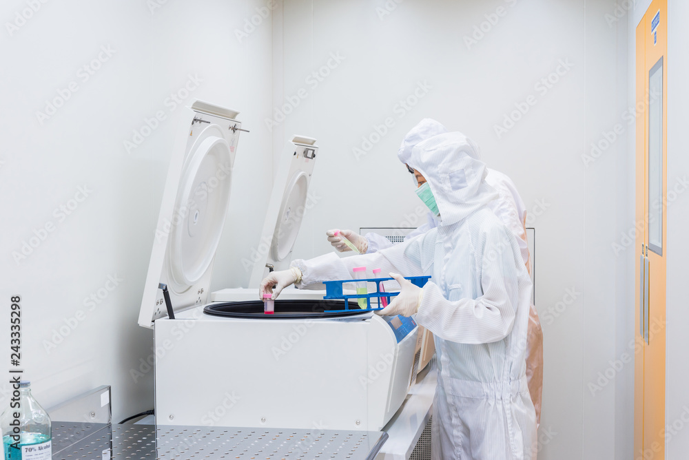 A scientist in sterile coverall gown placing cell culture flasks in the ...