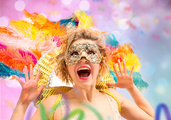 Wall Mural - Beautiful surprised woman in carnival mask. Beauty model woman wearing masquerade mask at party over holiday background with magic glow. Christmas and New Year celebration. Glamour lady with perfect