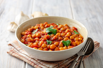 Wall Mural - Spicy Chickpea curry Chana Masala in bowl on wooden table. Traditional Indian dish. Selective focus.