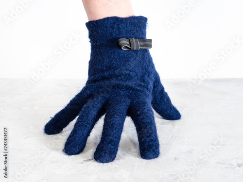 Fotografija hand in blue glove with bow tie leans on board