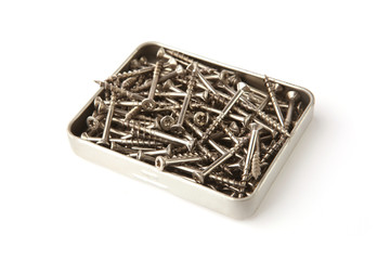 Stainless steel screws in box isolated on white background. Pile of wood screws.