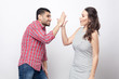 © khosrork - high five. Profile side view portrait of happy handsome man in red checkered shirt and beautiful woman in white striped dress standing and celebraiting victory.