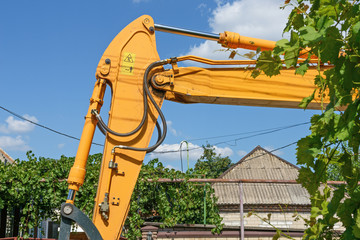 Close-up details of road-building  machine painted yellow on sky background.