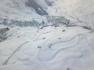 Wall Mural - Aerial view of snow covered road with curve used as ski slope for downhill skiing in Switzerland.