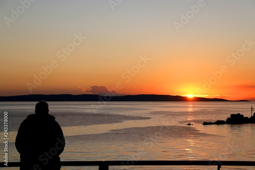 Foto Silhouete of an unecognizable man watching sunset over the sea.