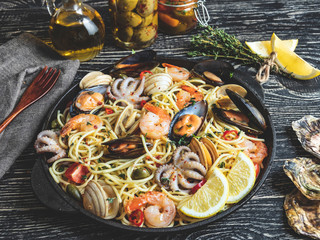 Wall Mural - Cooked pasta with clams, shrimps, baby octopus, mussels tomato on a frying pan , spaghetti