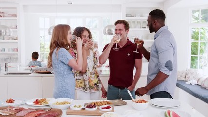 Wall Mural - Multi-Generation Family And Friends Making A Toast In Kitchen At Celebration Party