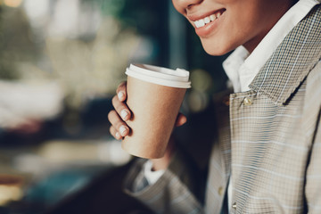 Wall Mural - Smiling woman holding brown cup of coffee in hand