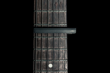 guitar part, neck with capo on a black background