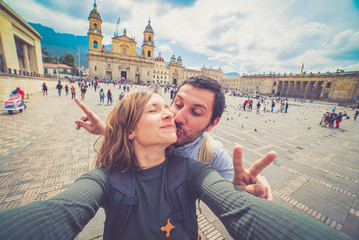 Wall Mural - Happy beautiful tourist couple taking a selfie photo in Bogota, Colombia. in the main square of the city called Bolivar square