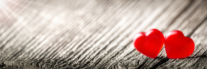 Wall Mural - two soft red hearts on vintage wooden table with sunlight