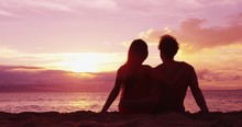 Couple Sitting Romantic At Beach Sunset In Love At Honeymoon Vacation Travel