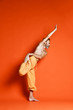 Old man practicing yoga doing stretching exercises against orange background