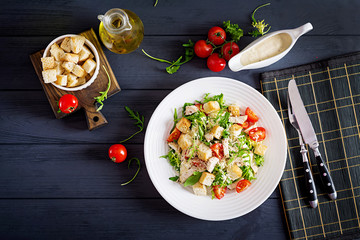 Healthy grilled chicken Caesar salad with tomatoes, cheese and croutons. North American cuisine. Top view