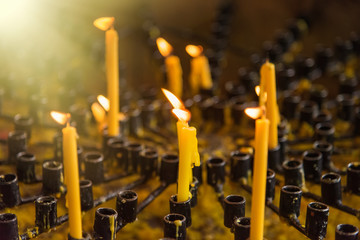 Burning wax candles in a Buddhist temple close-up. Rituals of worship of deities and gods in Asia. Meditation and worship of deities in Buddhism.