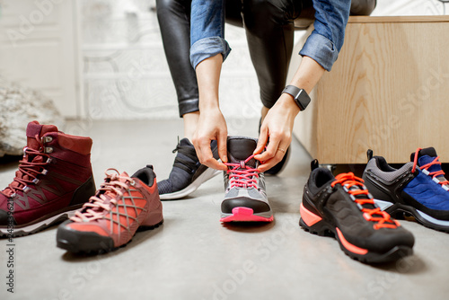 Cuadros en Lienzo Woman trying different trail shoes for mountain hiking in the sports shop, close