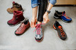 Woman trying different trail shoes for mountain hiking in the sports shop, close-up view with no face