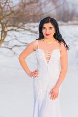 Arabic sexy woman in bright white chiffon long dress at snowy field. Evening fashionable dress, modern romantic bride ,winter fairytale 