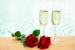 Two champagne glasses with rose flower next swimming pool.