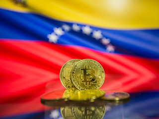 Wall Mural - Bitcoin gold coin and defocused flag of Venezuela background. Virtual cryptocurrency concept.