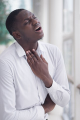 Wall Mural - Sick African man with sore throat; Portrait of ill black man suffering from sore throat due to cold, flu, allergy, polluted air, dust, smog; air pollution sickness concept; African man model