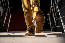 Bottom View Of A Young Man Walking Down The Stairs In Yellow Pants