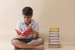 © IndiaPix - Boy Reading Book While Sitting On Floor Against Wooden Wall