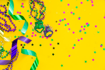 Mardi gras carnival concept - beads on yellow background, top view