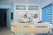 Two smiling nurses working at hospital reception desk
