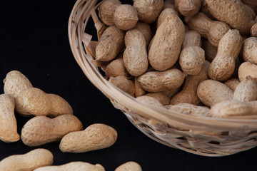 peanuts in a wicker basket on a black background