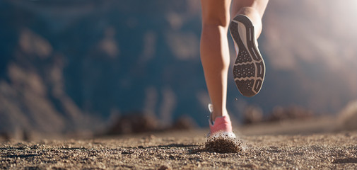 Wall Mural - Running shoe closeup of a woman running on a gravel path with sports shoes in a mountain environment