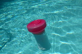 Fototapeta Natura - Close up of a floating swimming pool chlorine dispenser in sparkling clean water.