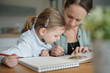 © goodluz - Mother and young daughter drawing and reading together at home