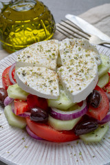 Wall Mural - Traditional greek salad made with fresh cucumber, tomato, paprika, red onion, kalamata olives, white salted feta cheese with oregano served with olive oil