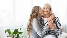 Young Daughter Kissing Senior Mother On The Cheek
