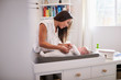 © Monkey Business - Happy mother changing the diaper of her newborn son at home on changing table, selective focus