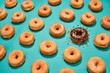 © Ben Goldstein - chocolate frosted donut in a lineup of glazed donuts