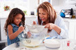 © Monkey Business - Young Hispanic girl making cake in the kitchen with her grandma, close up