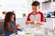 © Monkey Business - Brother and sister preparing cake mixture together at the kitchen table, waist up