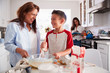 © Monkey Business - Pre-teen boy making a cake in the kitchen with his grandmother, his mum standing in the background