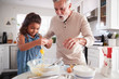 © Monkey Business - Young girl breaking an egg into cake mixture with her grandfather at the kitchen table, close up